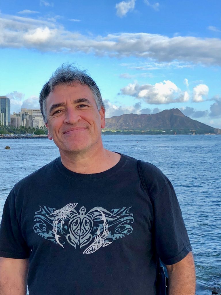 Philip L. Hirschhorn smiles in front of a body of water